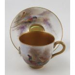 A Royal Worcester cabinet cup and saucer, hand painted with pheasants in a landscape to the exterior