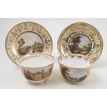 Two 19th century Derby porcelain tea cups, decorated with reserves of buildings in landscape to a