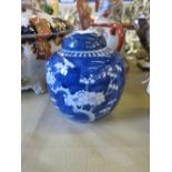 A Chinese covered ginger jar, decorated with prunus to a deep blue ground, with two circle mark to