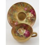 A Royal Worcester cabinet cup and saucer, hand painted with roses to the interior and exterior of