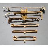 A yellow metal stock pin, formed as a hunting crop with foxes mask and having ruby eyes,