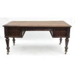 An oak writing table, fitted with a carved frieze drawer flanked by two carved drawers to each side,