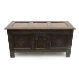 An oak coffer, the rising lid of three plain fielded panels, the front with three carved panels,