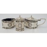 A set of three silver condiments, comprising hinged mustard, open salt and pepper pot,