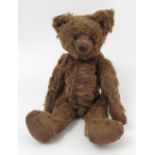 A brown plush bear, having stitched features, button eyes, hump back,