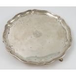 A silver salver, of circular shaped outline with moulded border, raised on three supports,