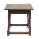 An Antique oak joint stool, having a carved frieze, raised on turned legs united by stretchers,