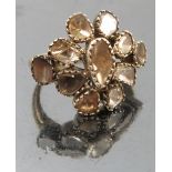 A diamond ring, set with eleven rough cut diamonds forming a flower head,