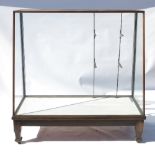 A shop display cabinet, with glazed sides and sloping front, having strut shelving bars,