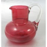 A 19th century cranberry glass jug, with clear handle and bulbous handle, height 6.