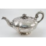 A Victorian silver tea pot, of squat lobed form with engraved decoration and flower finial,