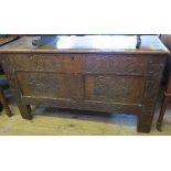 An Antique oak coffer, having rising lid over two carved panels with further carved decoration,