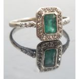 An emerald and diamond panel 18ct white gold ring, the step cut stone, 6mm by 4mm,