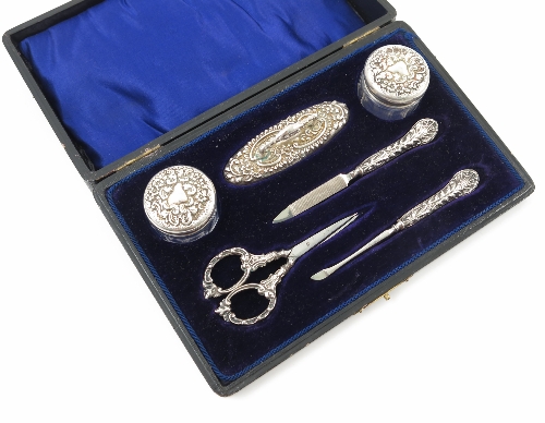 A cased silver manicure set, comprising two glass and silver topped bottles, a nail buffer,