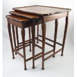 A nest of three walnut tables, of shaped rectangular form, raised on slender legs and pad feet,