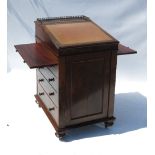 An early 19th century rosewood davenport, with rising lid fitted with a pull out slide to each side,