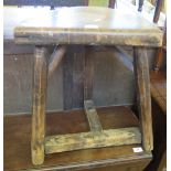 A primitive style stool, the D-shaped top raised on three legs and T base,