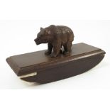 A Black Forest carved bear, mounted onto a wooden desk blotter,