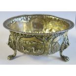 A silver circular bowl, embossed with a fox, birds and buildings, with lion mask and paw feet,