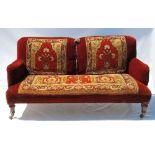 A 19th century sofa, with carpet style decoration, raised on short turned legs,