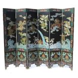An ebonised Oriental six fold screen, decorated in the Chinese style, with dragons,
