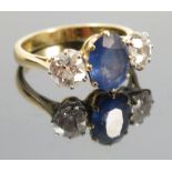 A three stone sapphire and diamond 18ct gold ring, the oval cut sapphire 9mm by 7mm,