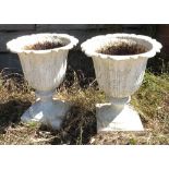 A pair of Regency style cast metal urns, raised on circular bases, height 22.5ins, originally from