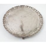 A silver salver, with shaped ogee edge, presentation inscription and raised on four scroll feet,