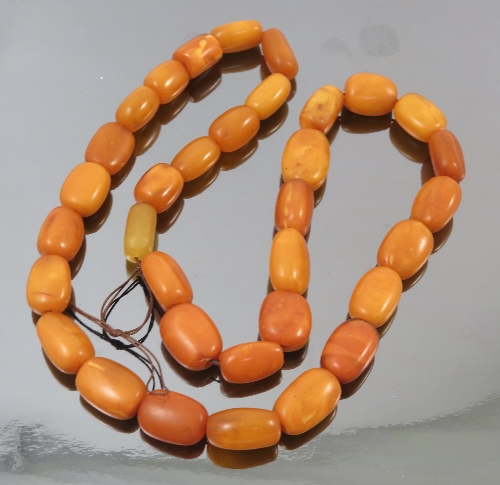 An amber bead necklace, composed of thirty-three oval beads,