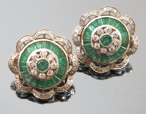 A pair of emerald and diamond cluster ear clips, the central emerald enclosed by eight diamonds,