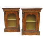 A pair of walnut pier cabinets, with marquetry inlay and ormolu mounts, having shaped glazed doors,