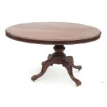 An oval mahogany loo table, raised on a column terminating in four scroll legs,