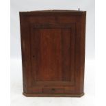An oak corner cupboard, with plain panelled door opening to reveal two shaped shelves,