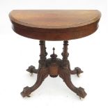 A 19th century half round fold over games table, raised on four turned columns,