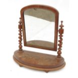 A mahogany swing frame toilet mirror, raised on barley twist supports, on a bow front base,