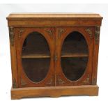 A 19th century walnut display cabinet, the two oval glazed doors opening to reveal shelves,