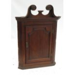 A Georgian oak corner cupboard, with swan neck pediment and arched fielded panel door,