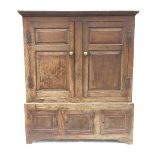 An 18th century oak cupboard on stand, having two twin fielded panelled doors to the upper section,