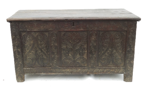 An oak coffer, with plain rising lid and three carved panels to the front,