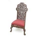 An Eastern hardwood nursing chair, with pierced foliate back and turned columns,