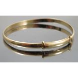 A 9ct gold expanding bangle, of plain shallow D section, weight 9.