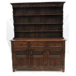 An oak dresser, with close boarded Delft rack over three drawers to the base,