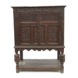 An Antique carved oak cupboard, having part carved doors, raised on a stand,