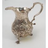 A George II silver cream jug, with scroll handle, embossed floral decoration and vacant cartouche,