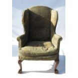 An Antique wing armchair, in the Georgian style, raised on front slender cabriole legs,