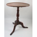 A late Georgian oak and mahogany circular tripod table, with dish top and standing on a tripod base,