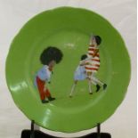 A child's Continental porcelain plate, transfer decorated with toys playing on a green ground,