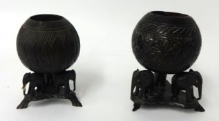 Two Indian carved coconut shells on ebonised elephant stands, 21cm
