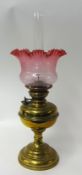 Brass oil lamp with cranberry glass shade, 46cm