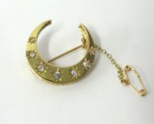Yellow metal crescent brooch set with seven diamonds, approximately 30mm wide